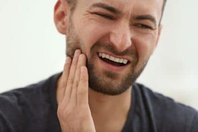 man holding his jaw in pain