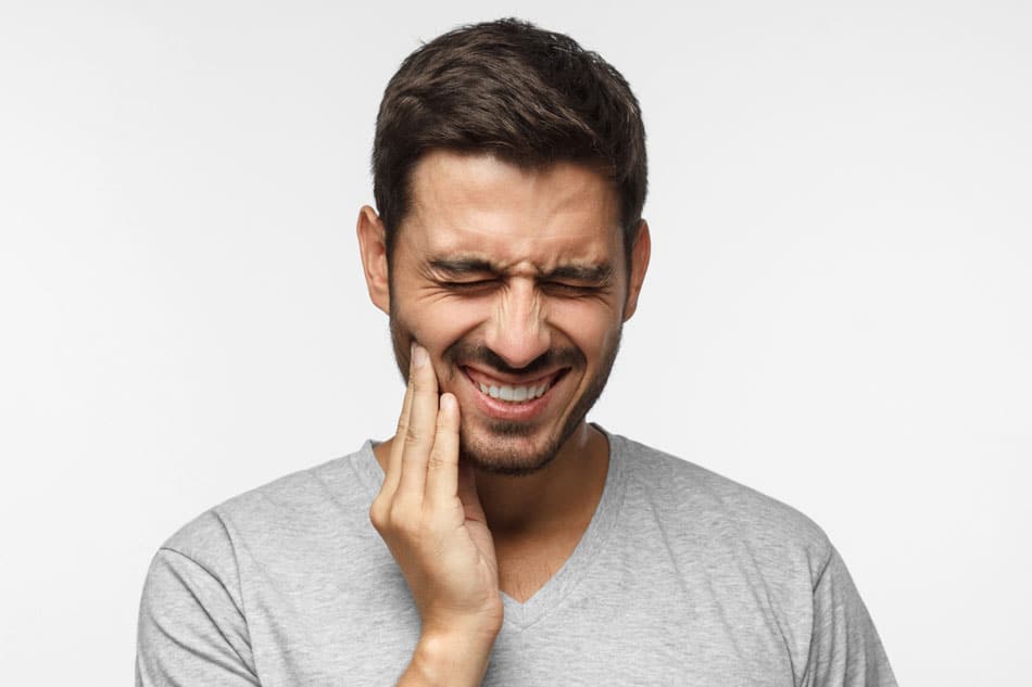 young adult man holding his jaw in pain