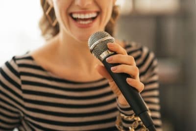 upclose photo of woman singing into a microphone