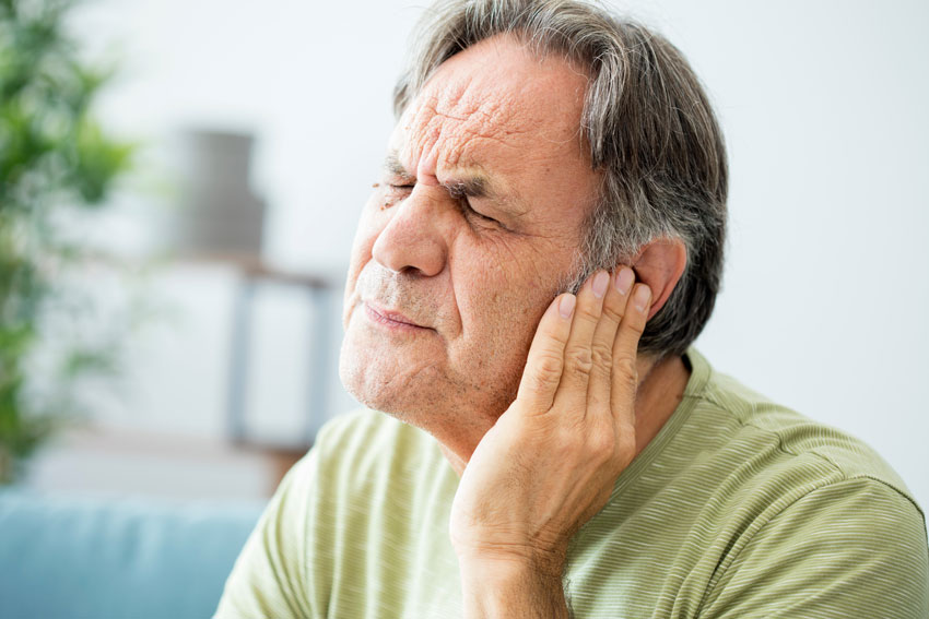 senior man with ringing in ear tinnitus