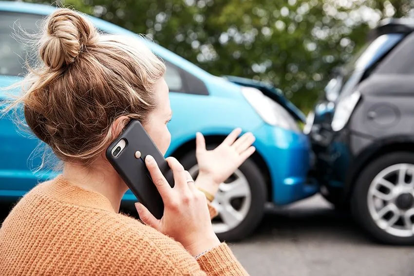 woman talking on her cell phone after getting into a car accident
