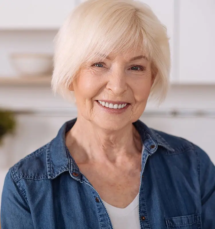 Older woman shows off her smile in her kitchen