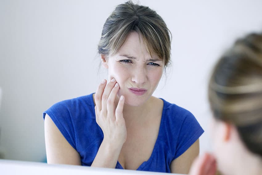 woman looking in the mirror with jaw pain
