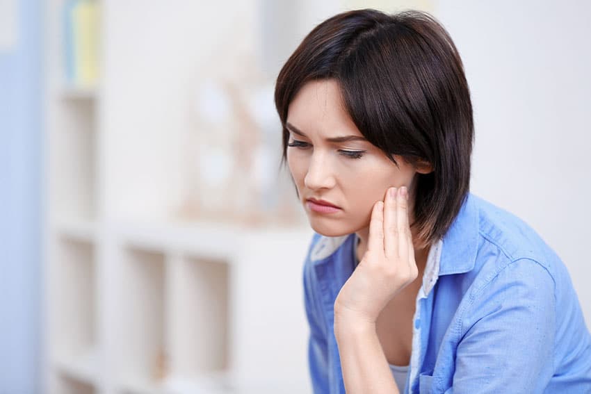 woman sitting at home with tmj pain, or is it tmd?