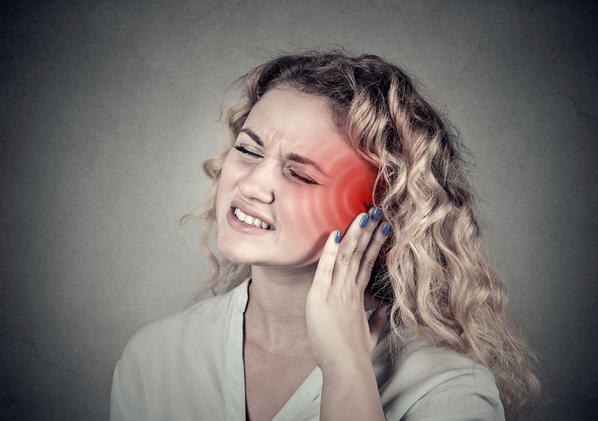 woman holding her ear in pain