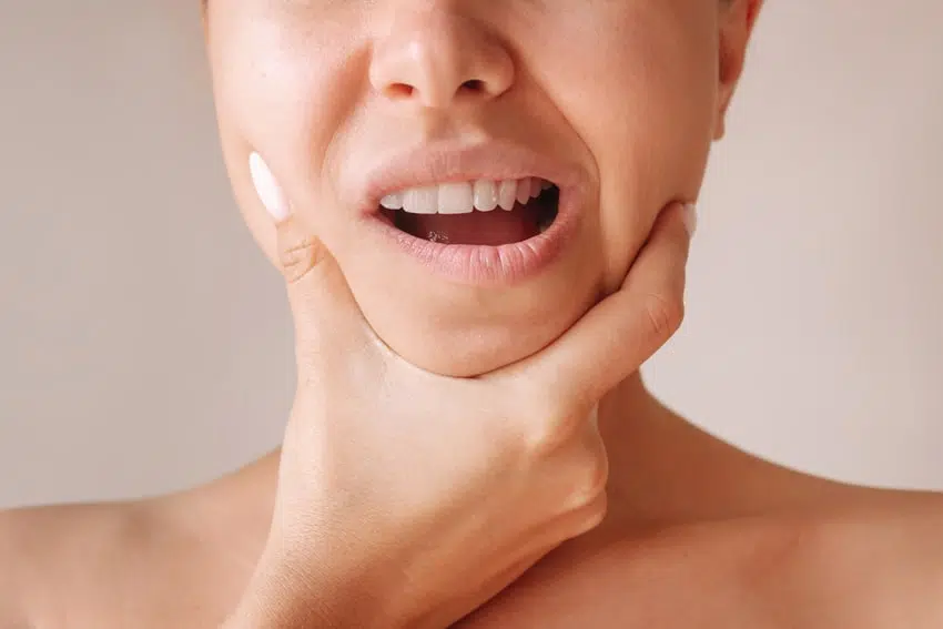 adult holding their jaw in discomfort